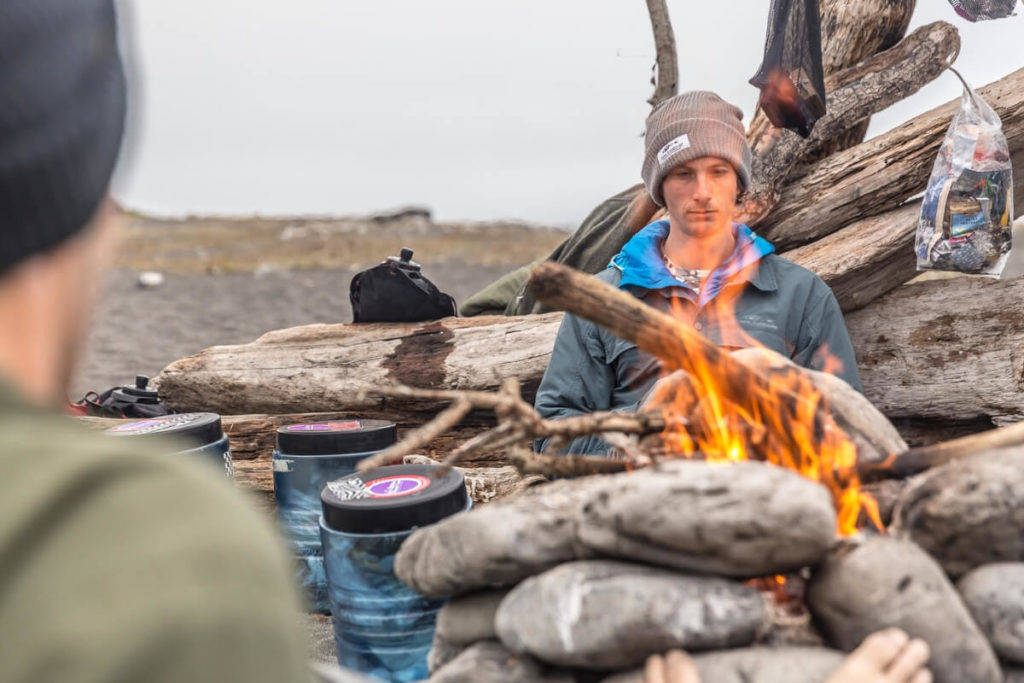 Man in front of campfire on beach